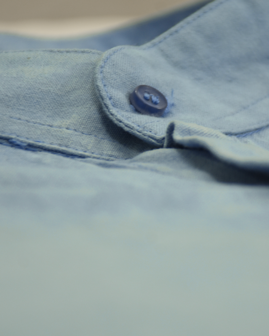 Close-up of a button on a light indigo shirt